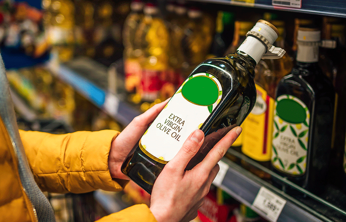 Woman looking at bottle of extra virgin olive oil at supermarket