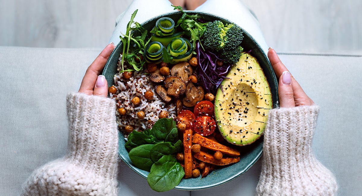 Woman eating a plate of vegetables. Plant-based diets have substantial health benefits.