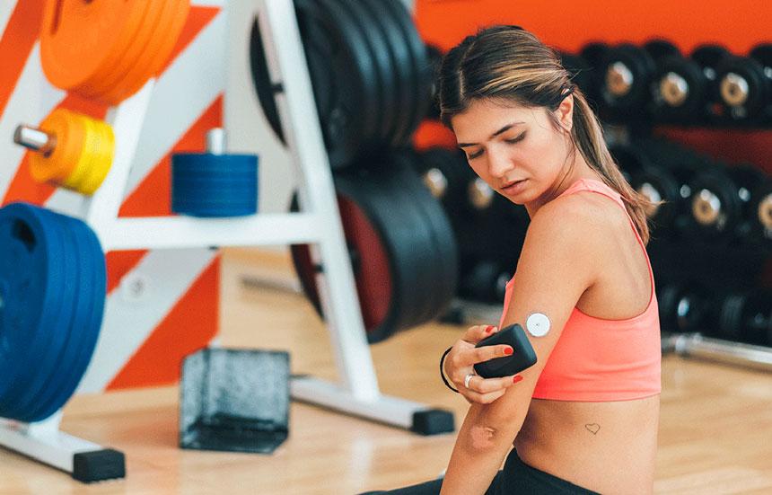 female using glucose monitor while sitting in front of weights