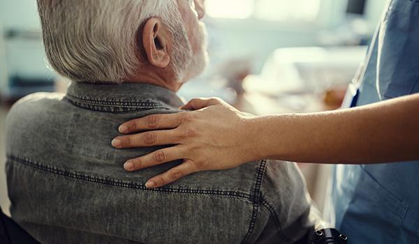 A nurse consoling an elderly man