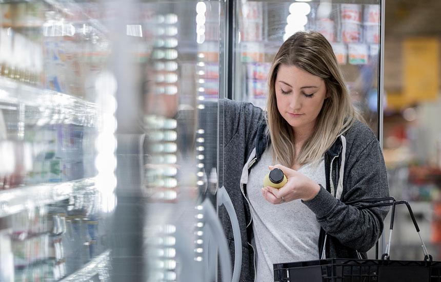 Woman shopping for almond milk at supermarket