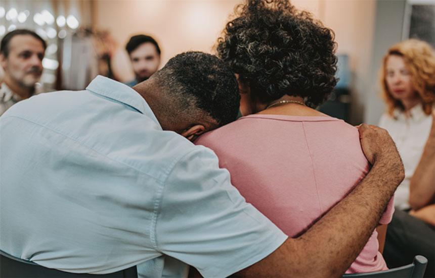 Two people hug during a grief support group meeting.