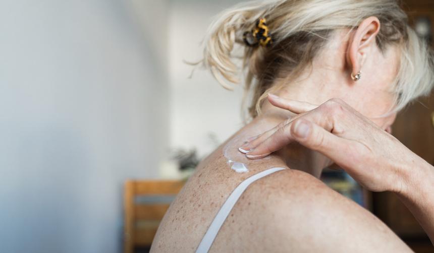 Woman applies lotion to her skin