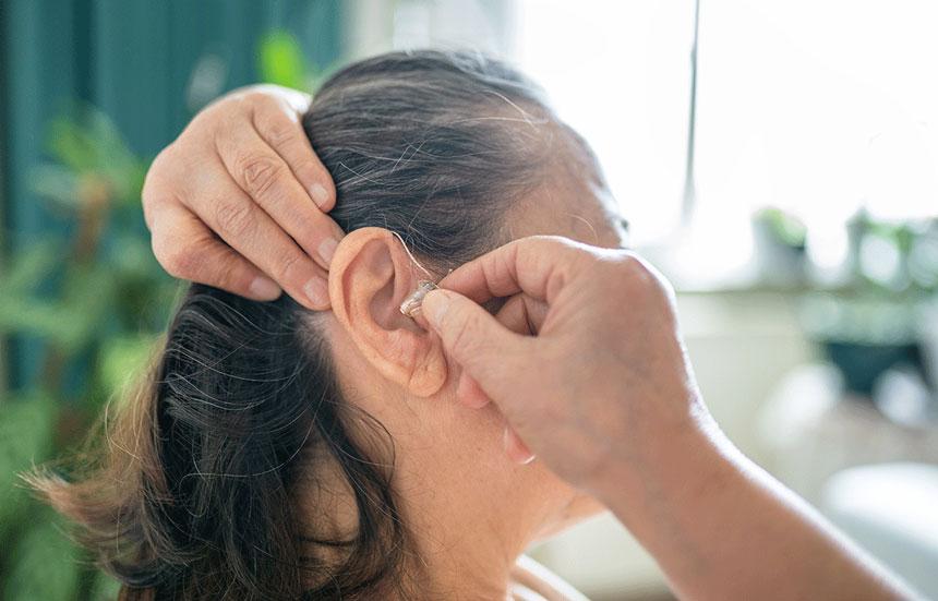 Woman putting on a hearing aid