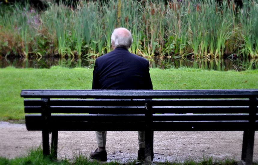 A older man sitting alone on a bench. Loneliness and social isolation can lead to real health issues.