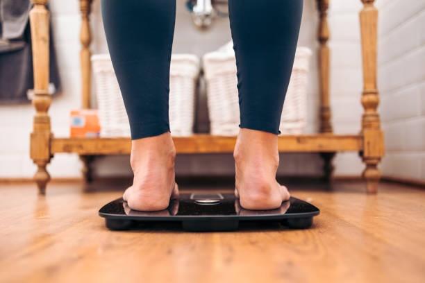 woman in a bathroom weighing herself on a scale