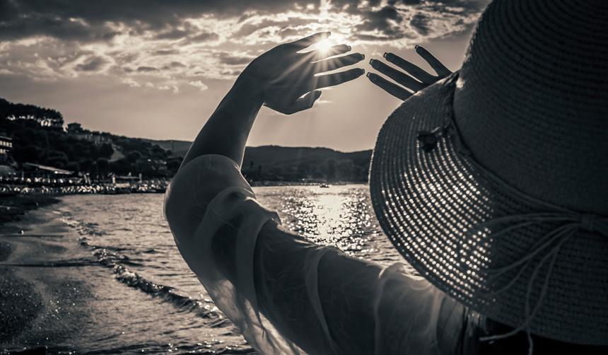 A woman wears a hat and log sleeves to protect her skin from the sun.