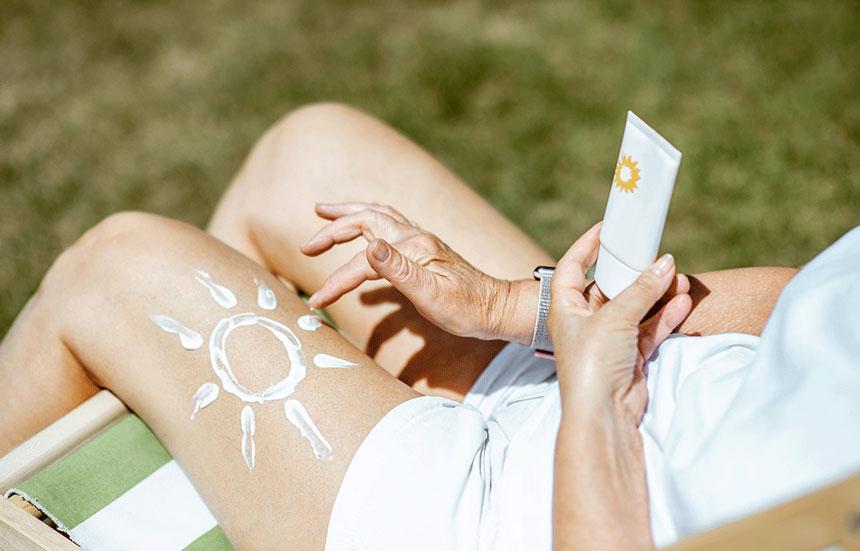 Woman with a sun drawn on leg with sunblock