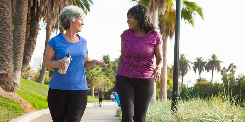 two middle aged women walking and holding water bottles