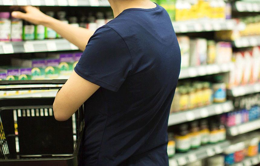 grocery shopper picking up supplement from shelves