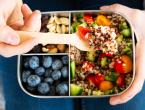 Person using spoon to lift fruit, nuts, vegetables and grains from a food tray