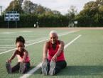 Grandmother and granddaughter stretching on football field